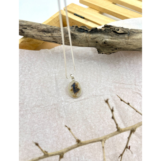 Forest Echo Shazar silver pendant by Ochrello with central dark dendritic inclusions resembling trees, styled on driftwood and textured background.