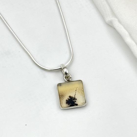 Close view of the agate’s warm gradient surface with a single bold dendritic pattern resembling a lone bloom in a desert landscape.