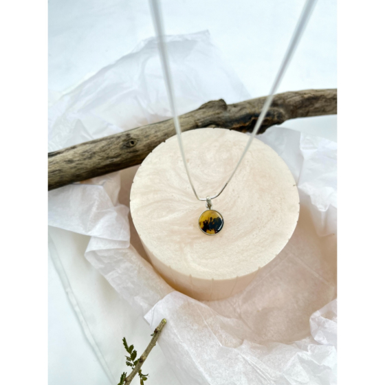 Pendant styled against soft beige textures and driftwood, reflecting a rustic, twilight-inspired mood in the natural composition.