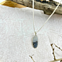 Styled image highlighting the pendant’s handcrafted silver bezel and the natural tree-like inclusions in the gemstone.