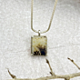 Close-up of Forestfall Light pendant showing intricate golden dots and dark dendrites in a rectangular gemstone, handcrafted in silver.