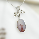 Coral colored Shazar silver pendant by Ochrello featuring soft pink dendritic patterns and a handcrafted dragonfly-shaped silver detail.