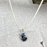 Close-up of the stone’s dark blue dendritic branches rising through a cloudy white matrix—evoking twilight trees in moonlight.